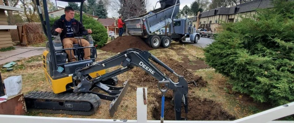 Excavator digging in residential yard area in Denver, CO.